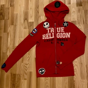 True Religion - Skit fet och unik True Religion hoodie, köpt på second-hand för längesedan och är såvitt jag vet den enda av dess slag. Storlek S men sitter som M eftersom den är lång men slim. Pris kan diskuteras, skriv om du har frågor!!