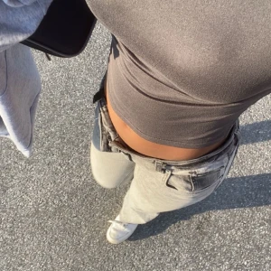 Lågmidjade Jeans(lager 157)  - Säljer en stilren grå croppad topp med tight passform. Perfekt för en avslappnad look eller att styla upp med accessoarer. Toppen är ärmlös och gjord i ett mjukt material.