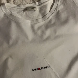 Saint Laurent T-Shirt  - Säljer nu min riktigt snygga Saint Laurent T-shirt i grymt skick förutom en fläck där fram, knappt synlig. Inget speciellt utan blev så efter jag tvättade den🤷‍♂️ nypris på cirka 2499kr! Hör av er vid frågor & funderingar!🤝