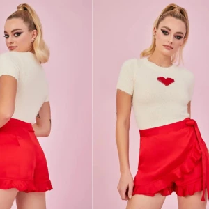 Röda shorts från Sugar Thrillz - Love That's The Tea Wrap Skort (märke: Sugar Thrillz), köpt på Dollskill för ca 560 kr och är för tillfället slutsåld på hemsidan. Röda shorts med snörning i midjan. Använd några gånger men fortfarande fint skick. Storlek S.  Rökfritt hem men har katter.