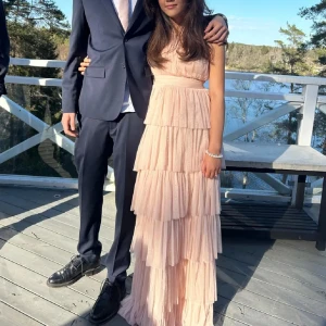 Ljusrosa balklänning med volanger - Elegant ljusrosa långklänning med flera lager av volanger. Klänningen har en oneshoulder-design som ger en stilren och modern look. Använd ca 3 ggr, 1 gång av förra ägaren o 2 ggr av mig. Har en defekt med fläckar längst ner på klänningen som går ca 10cm upp. Går att få bort genom att sy upp klänningen, men går ej bort i tvätten. Kom gärna med prisförslag!