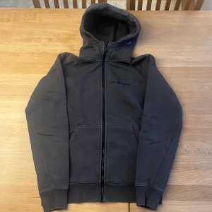 Sail racing hoodie med dragkedja - Säljer en oliv färgade hoodie med dragkedja och huva. Tröjan har långa ärmar och en klassisk design med fickor framtill. Perfekt för en avslappnad stil. Inte sliten alls 