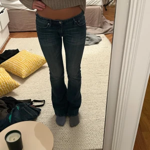 Mörkblå bootcut jeans - Snygga mörkblå bootcut jeans med låg midja. Perfekta för en avslappnad stil. Klassisk femficksdesign och knappgylf.