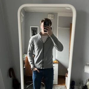 Grå tröja med dragkedja från Jerem Collection - Säljer en grå zip tröja från något som heter Jerem collection. Den är i helt okej skick, inga defekter bara dragkedjan som kan strula ibland. Annars en väldigt schysst tröja!