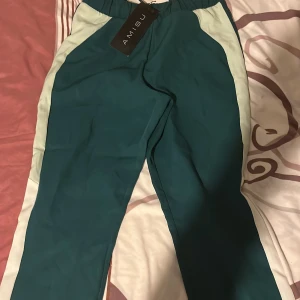 Gröna byxor från Amisu - Snygga gröna byxor från Amisu med vita sidopaneler. De har en elastisk midja och är perfekta för en avslappnad stil. Byxorna har en bekväm passform och är lätta att matcha med olika toppar.