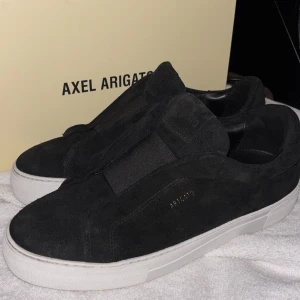 Axel Arigato skor  - Snygga svarta sneakers från Axel Arigato med vit sula. Dessa stilrena skor har en ren design med diskret logga på sidan- perfekta för en avslappnad men trendig stil. De kan behöva en snabb rengöring av mockan för att se helt nya ut igen. Jag köpte dom via Axel Arigato, men tyvärr var storleken fel för mig. Jag har storlek 41 och trodde att 43 skulle passa, men den är för små. Pris kan diskuteras vid snabb affär endast!