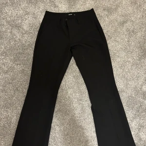 Svarta kostymbyxor - Snygga svarta kostymbyxor med en klassisk straight passform. Perfekta för en stilren look. Byxorna har en diskret dragkedja och knapp framtill.