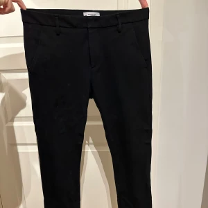Svarta byxor från Dondup - Snygga svarta byxor från Dondup i fint skick. Stilren design med knappar bak. Strl 31