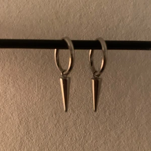 Silverörhängen med konformade hängen från Edblad  - Snygga silverörhängen med små ringar och konformade hängen. Perfekta för att ge en edgy touch till din stil. Lätta att matcha med olika outfits. Från Edblad, använt cirka 5 gånger. Köpt för 400kr. Får med asken också