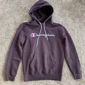 Brun hoodie från Champion - Säljer en brun hoodie från Champion med klassisk logga på bröstet och en liten logga på ärmen. Tröjan har en stor ficka framtill och justerbar huva med snören 😎 