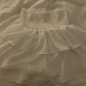 Vit kjol från Chelsea - Säljer en söt vit kjol från Made by Chelsea. Kjolen har en elastisk midja med smockdetaljer och ett flödande tyg som ger en fin volang-effekt. Perfekt för en somrig look!