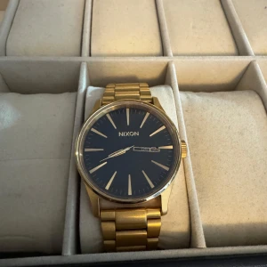 Guldfärgad klocka från Nixon - Snygg guldfärgad klocka från Nixon som är snålt använd. Nypris 2 700kr. Tveka inte på att höra av dig vid frågor eller funderingar Med vänlig hälsning Carl 