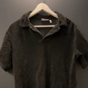 Grå pikétröja från Weekday - Säljer en stilren grå pikétröja från Weekday i storlek XS men sitter som s Tröjan har korta ärmar och en klassisk krage, perfekt för en avslappnad look. Passar bra till både jeans och chinos.