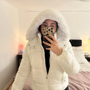 Vit dunjacka med pälskantad huva - Säljer en snygg vit dunjacka med en mysig pälskantad huva. Jackan är endast använd en gång, ny pris är 499 