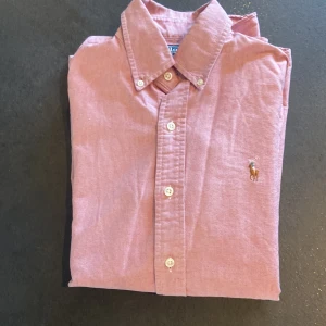 Polo Ralph Lauren skjorta rosa - Snygg polo skjorta som knappt  andvänd någon enstaka gång bara. Har legat i min garderob i något år nu. Andledning är att jag växt ur den. Skriv om ni har ytligare frågor eller vill se fler bilder.                        Ny pris ligger på 1400- 1600kr mitt pris är 400 för en näst intill oandvänd polo skjorta!!