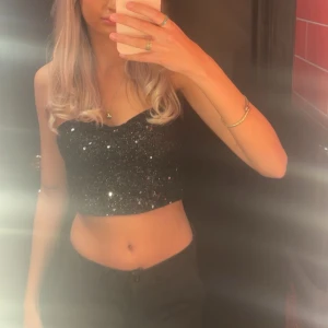 Svart glittrig tubtopp - Säljer en snygg svart glittrig tubtopp som är perfekt för festliga tillfällen. Passar utmärkt till både kjol och byxor för en kväll ute🤩