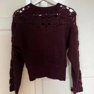 Vinröd stickad tröja från Zara - Säljer en vinröd stickad tröja från Zara med vackra virkade detaljer på axlar och ärmar. Tröjan har en rund halsringning och långa ärmar. Perfekt för att ge en elegant touch till din garderob. 🌟