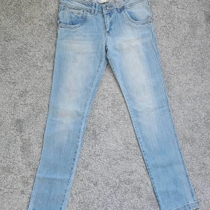 Ljusblå jeans från Tudor - Snygga ljusblå skinny jeans  med diskreta slitningar. Verkligen lågmidjade, och Tajta. Köpt för 30 år sedan,  aldrig använd! Vintage plagg! Det står bomull 98% elastan 2% men det är ej stretchiga bara sköna. Midjemått ( faktiskt höfterna 42*2 och väldigt långa 83 cm innerbensmått! W30 L 34 