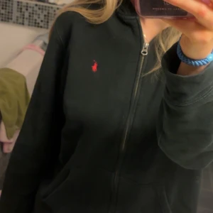 Ralph Lauren hoodie - Snygg svart hoodie från Ralph Lauren med dragkedja och huva. Nypris 1195kr. Mycket bra skick, säljs för 500kr