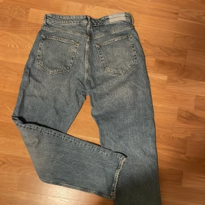 Blå jeans från Karve - Snygga blå jeans från Karve med klassisk femficksdesign och knappgylf. Perfekta för en avslappnad stil. De har en rak passform och är tillverkade i slitstarkt denim. Byxorna är gjorda så att de ska se lite klassiskt använda ut runt fickorna, men är helt nya och knappt använda! 