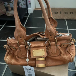 Chloe Paddington bag  - Chloe Paddington väska i färgen camel. Väskan har slitningar på lädret och har tappat lite färg på låset. Bredd: 37 cm, Höjd: 16 cm, Djup: 16 cm. Köpt på Vestiaire, där jag betalde extra för autentisering.