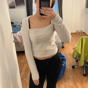 Vit offshoulder topp - Säljer en stilren vit offshoulder topp med lång ärm. Perfekt för både vardag och fest! Toppen har en tight passform som framhäver figuren. Den är i mycket bra skick och passar perfekt till både jeans och kjol.