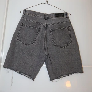 Grå jeansshorts med råa kanter - Säljer ett par grå jeansshorts från Bik Bok i storlek M. De har en cool, rå kant och klassisk femficksdesign. Perfekta för en avslappnad sommarlook. Passar både till vardags och fest!