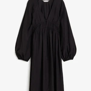 Svart långklänning med v-ringning - Elegant svart långklänning med v-ringad design och långa ärmar. Klänningen har en smockad detalj i midjan som ger en fin passform. Perfekt för höst- och vinterevenemang. Den första bilden är inte min men det är exakt samma modell/design💖 og pris: 300kr