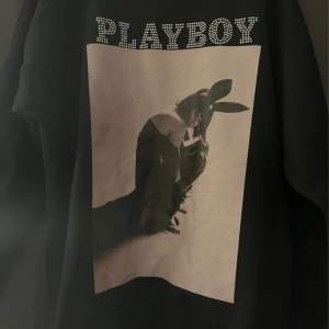 Säljer en svart sweatshirt från playboy x missguided med ett stort tryck på baksidan. Trycket visar en stilren bild i svartvitt och texten 'PLAYBOY' i glittriga bokstäver, perfekt för en cool och avslappnad stil🖤