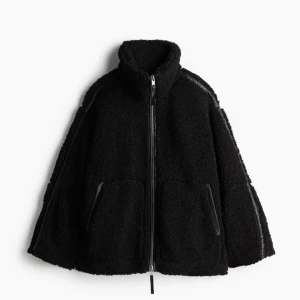 Svart teddyjacka med dragkedja - pilejacka med lös passform  - Mysig svart teddyjacka perfekt för kyliga dagar. Den har en dragkedja framtill och stora fickor för extra komfort. Jackan är långärmad och har en hög krage som håller dig varm. Aldrig använd med prislapp kvar!