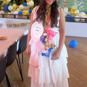 Vit långklänning med volanger - Superfin vit långklänning med volanger, perfekt för studenten\ mottagningen eller sommarens fester. Klänningen är ärmlös och har en v-ringad design som ger en romantisk känsla. Materialet är lätt och luftigt, vilket gör den bekväm att bära hela dagen. Passar perfekt för en somrig look! 🌸