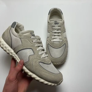 Valentino Garavani sneakers  - Säljer ett par snygga Valentino Garavani sneakers i beige och grå. De har en cool, mönstrad sula och är gjorda i en mix av mocka och syntetmaterial. Perfekta för både vardag och fest! Skorna har snörning och är i mycket bra skick. 43 passar 44