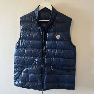 Moncler väst - Säljer en snygg blå dunväst från Moncler i mycket bra skick. 2 lappade hål som man inte ser annars inget fel på den. Dm för ytterligare info 