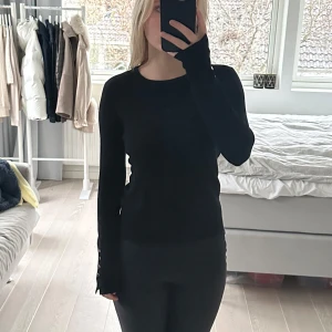 Svart långärmad tröja från Zara - Säljer en stilren svart långärmad tröja från Zara i storlek S. Tröjan har snygga knapplister vid ärmsluten som ger en extra touch. Perfekt för både vardag och fest! Den är i bra skick! Ej använd så mycket
