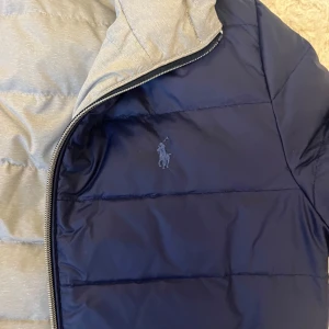 Ralph lauren jacka  - Säljer denna snygga jacka från Ralph lauren som kan vändas ut och in och fungerar därför som både grå och mörkblå jacka. Väldigt varm och bekväm. Storlek L i barnstorlek (14-16 år). Fungerar för både killar och tjejer!