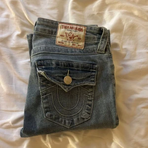 True Religion jeans i blå denim - Säljer du dessa as snygga True Religion jeansen. Jensen är ljusblå, Mid Rise Bootcut och storlek 26. Jag är 173 cm, och de sitter perfekt på mig. Jag köpte de i sommras nya för 1200kr, och har använt de ca 5ggr. Säljer för 800kr. De har inga skador, och är i nyskick. Har ej på köpnu, eftersom priset kan ändras