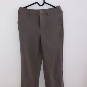 Beige kostymbyxor - Säljer ett par stiliga beige kostymbyxor i bra skick. De har en klassisk straight passform och är perfekta för både kontoret och mer formella tillfällen. Byxorna har en liten fläck, men det påverkar inte helhetsintrycket. Perfekta för höst och vår!