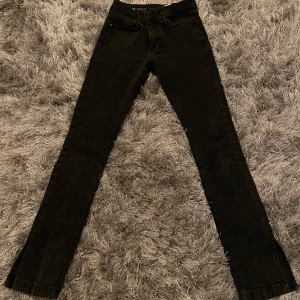Svarta slim jeans med slits - Säljer ett par svarta slim fit jeans med slits vid bensluten. Dom har inte något stretch men passformen blir väldigt fin. Säljer endast för att bli av med dom snabbt men som referens är jag 160cm och dessa passar perfekt på mig. 
