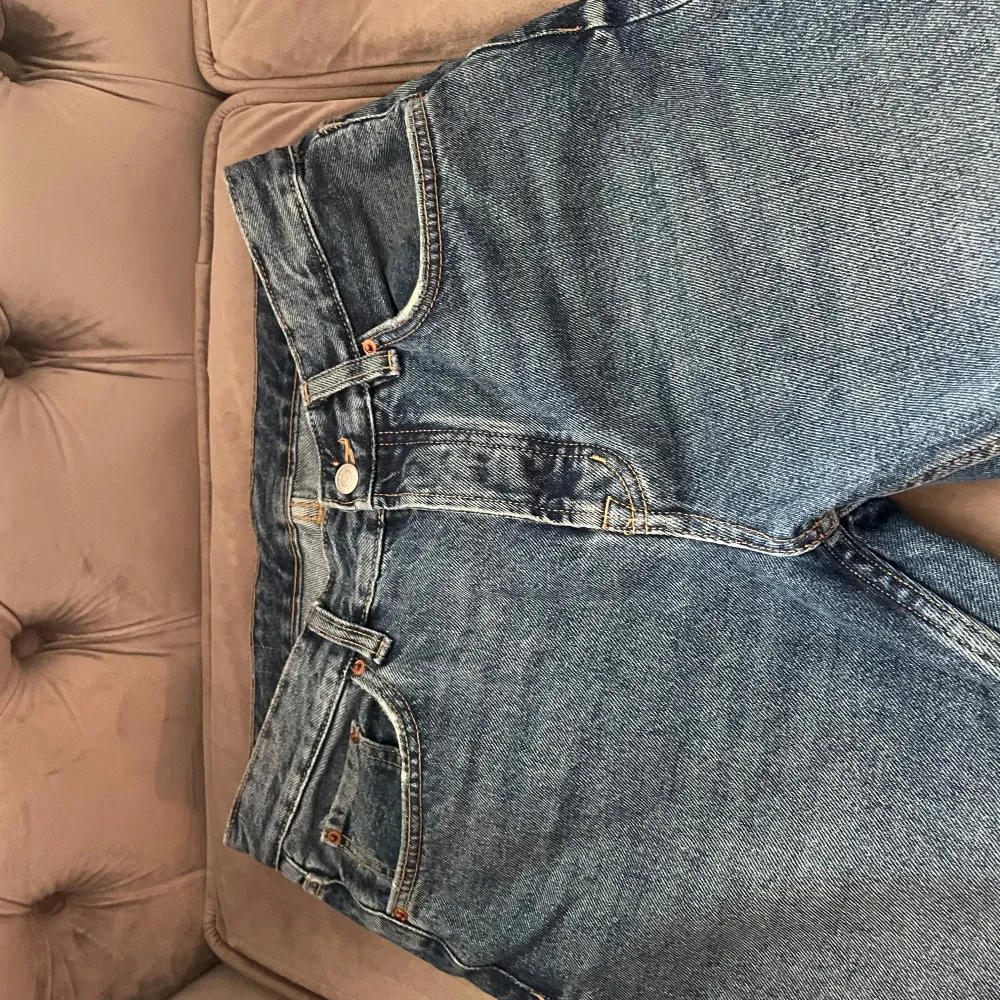 Säljer ett par klassiska blå jeans från Zara i bra skick. De har en normal passform med midwaist och raka ben. Perfekta för vardagsbruk och kan enkelt matchas med olika outfits. Jeansen har en dragkedja och knapp framtill samt fem fickor.. Farkut & Housut.