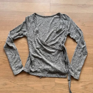Grå omlottopp - Säljer en snygg grå omlottopp med knytning. Lapp borta men ganska säker på att den är storlek xs och kommer från newlook