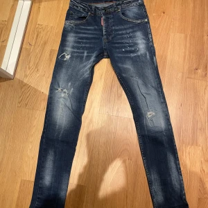 Dsquared2 jeans - Säljer ett par snygga blå jeans från Dsquared2 i bra skick. De har en cool slitning och distressed look på framsidan. Jeansen är midwaist och har en straight passform. Perfekta för en casual stil eller en utekväll. Storleken är XS.