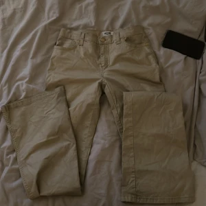 Beige byxor - Säljer ett par beige byxor i bra skick. De har en klassisk design med normal passform och är perfekta för vardagsbruk. Byxorna har fickor fram och bak samt en knapp och dragkedja i gylfen.