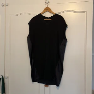 Svart silke klänning från AllSaints - Snygg svart klänning från AllSaints i japanskt raw silke. Den är ärmlös och har en stilren design som passar perfekt för både vardag och fest. Klänningen har en boxy passform och är gjord i ett otroligt fint tyg.