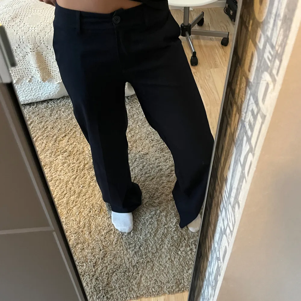 Säljer ett par stilrena mörkblåa kostymbyxor i mycket bra skick. De är lågmidjade/midwaist och har en straight passform som ger en klassisk look. De är otroligt sköna och väldigt fina❤️. Jeans & Byxor.