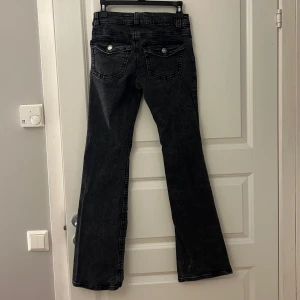 Svarta bootcut jeans - Säljer ett par snygga svarta bootcut jeans från Ginatricot i storlek 36. De har en klassisk femficksdesign med dragkedja och knapp framtill. Perfekta för både vardag och fest!