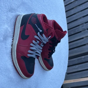 Nike Air Jordans i rött och svart - Säljer ett par klassiska Nike Air Jordans i rött och svart. Skorna har en snygg design med svart swoosh och röd ovandel. De har snörning i olika färger för en unik look. Perfekta för både vardag och fest! Säljs på pluck och vinted (först till kvarn)
