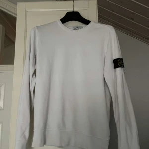 Vit tröja från Stone Island - Säljer en stilren vit tröja från Stone Island med deras ikoniska märke på ärmen. Tröjan är långärmad och perfekt för både vardag och fest. Den är i mycket bra skick och passar till alla tillfällen. Skön och enkel att matcha med andra plagg.
