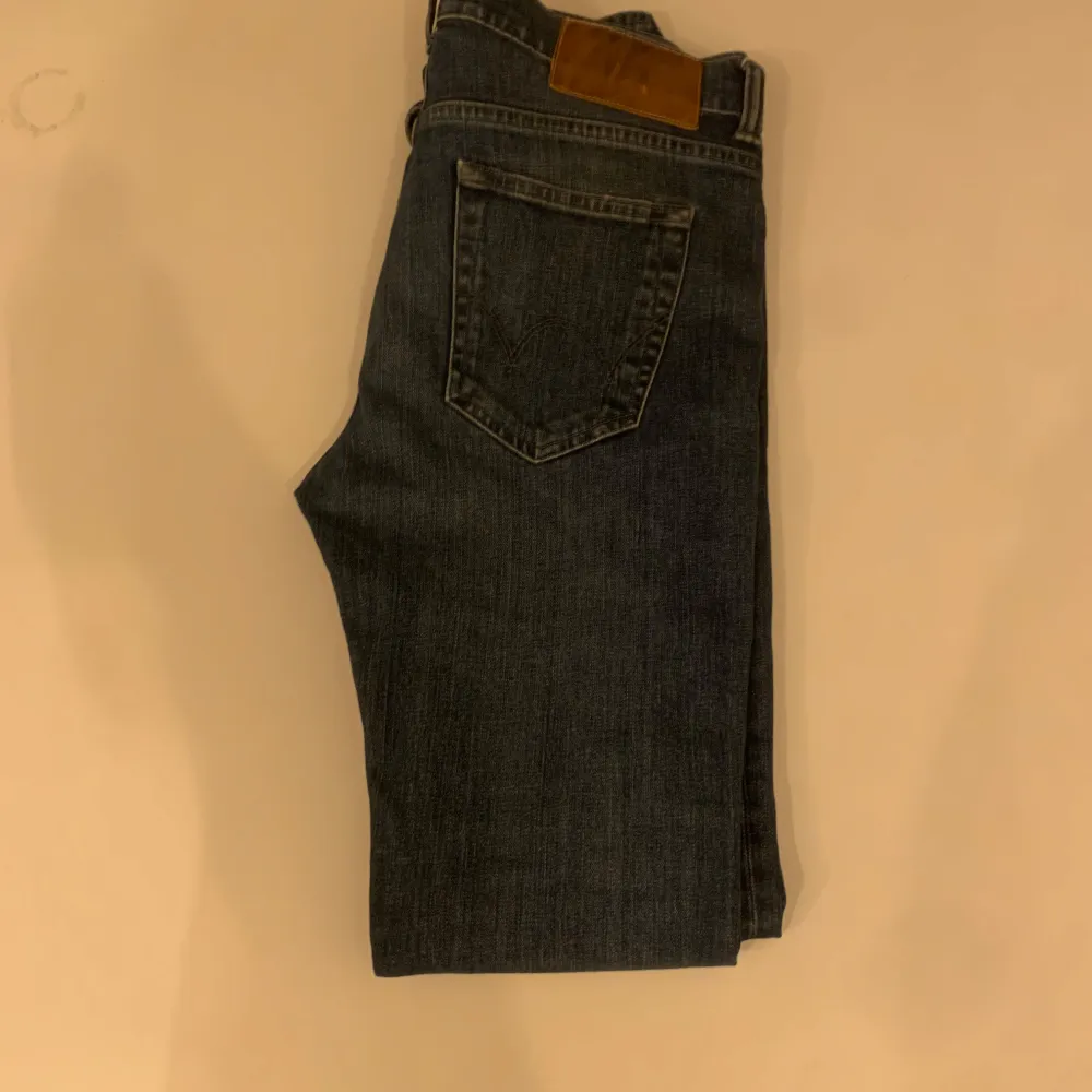 Säljer ett par snygga blå Edwin jeans, modell ED-80. De har en slim tapered passform som sitter perfekt. Klassisk femficksdesign med en läderpatch på baksidan. Perfekta för både vardag och fest!. Jeans & Byxor.