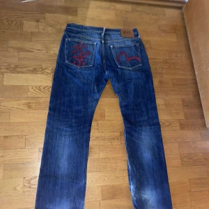 Blå evisu jeans med röd broderad detalj - Sköna evisu jeans från Japan med selvedge denim och röd tryck på baksidan