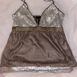 Glittrig topp från vero Moda  - Säljer en snygg glittrig topp från vero Moda i silver och sandfärg. Toppen har paljetter upptill som ger en festlig look. Perfekt för en utekväll eller festlig tillställning.
